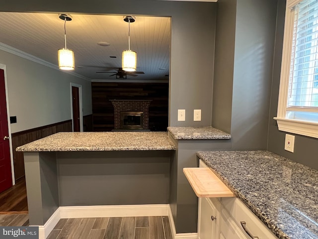 kitchen with dark wood finished floors, a ceiling fan, white cabinetry, ornamental molding, and light stone counters