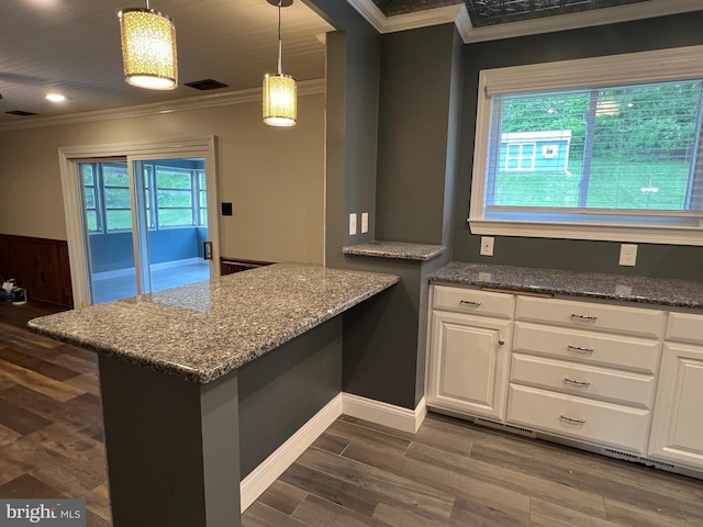 kitchen featuring crown molding, white cabinetry, a peninsula, dark wood-type flooring, and dark stone countertops