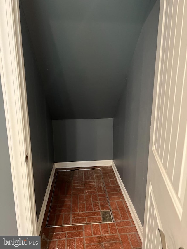 bonus room featuring brick flooring, baseboards, and lofted ceiling