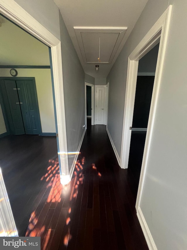 hallway with attic access, wood finished floors, and baseboards