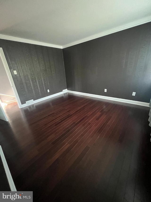 unfurnished room featuring dark wood-style floors, baseboards, and crown molding