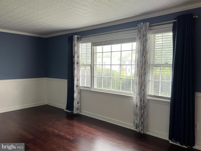 unfurnished room featuring wood finished floors, healthy amount of natural light, wainscoting, ornamental molding, and baseboards