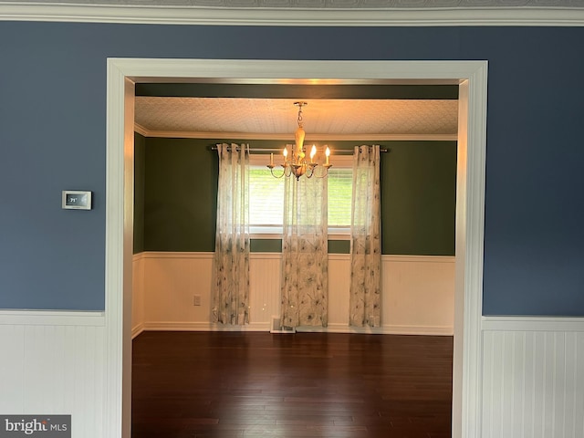 unfurnished dining area with wainscoting, a chandelier, hardwood / wood-style floors, and wooden walls