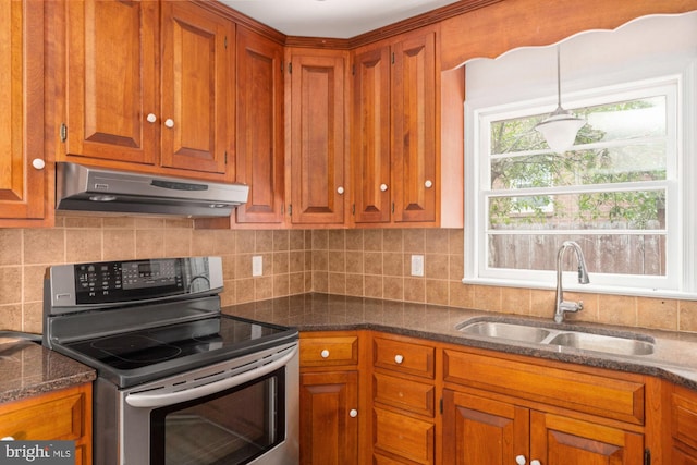 kitchen with stainless steel range with electric stovetop, under cabinet range hood, a sink, brown cabinetry, and tasteful backsplash