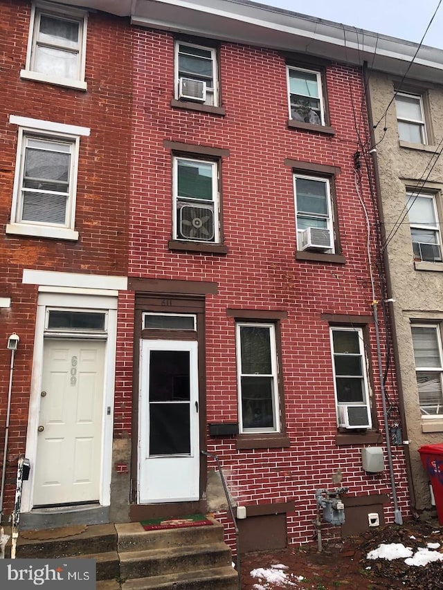 townhome / multi-family property with cooling unit and brick siding