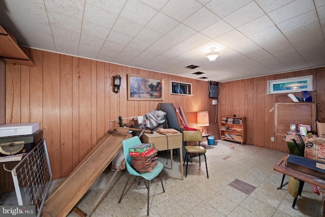 living area featuring tile patterned floors and wooden walls