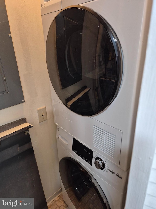 laundry room with estacked washer and dryer and baseboards