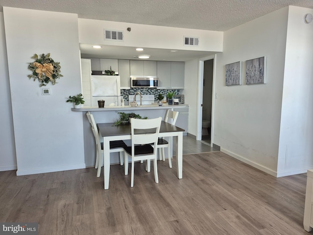 dining area with wood finished floors, baseboards, and a textured ceiling
