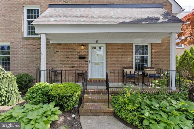 doorway to property featuring a porch and brick siding