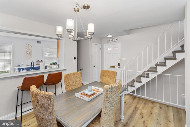 dining room with a chandelier, stairs, light wood-style flooring, and baseboards