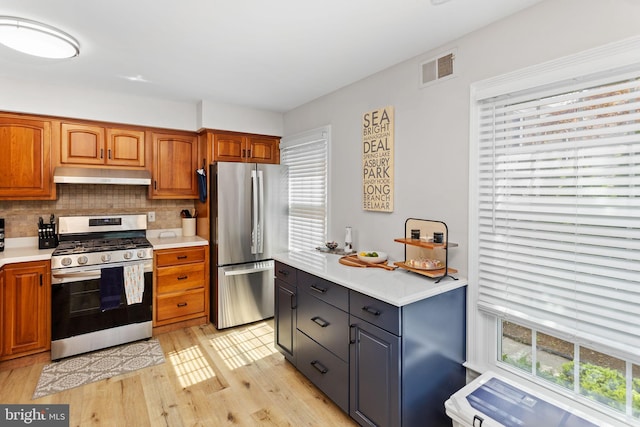 kitchen featuring stainless steel appliances, under cabinet range hood, healthy amount of natural light, and light countertops