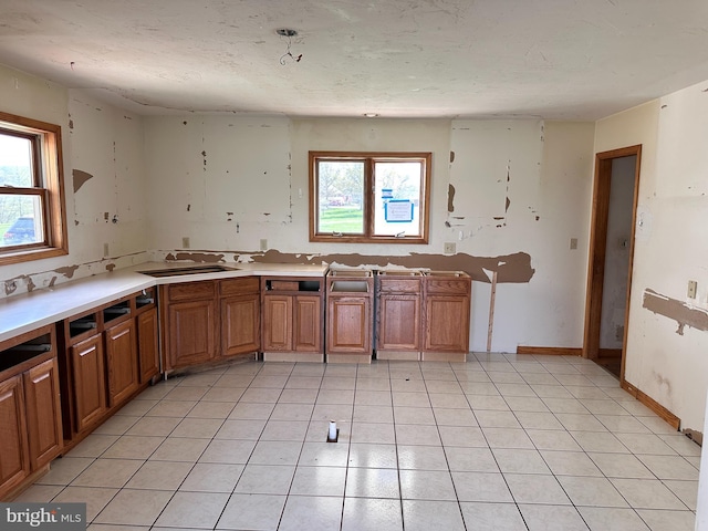 kitchen featuring a sink, brown cabinets, light countertops, and light tile patterned floors