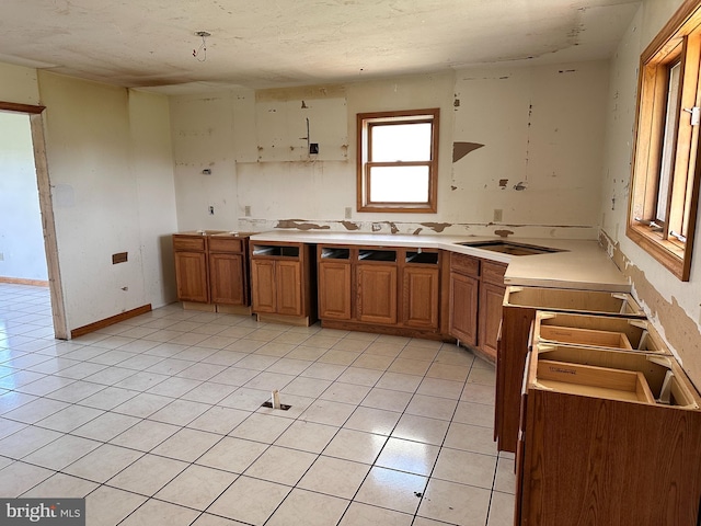 kitchen with brown cabinets, light tile patterned flooring, a sink, and light countertops