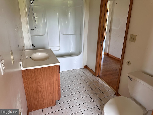 bathroom featuring toilet, tile patterned flooring, vanity,  shower combination, and baseboards