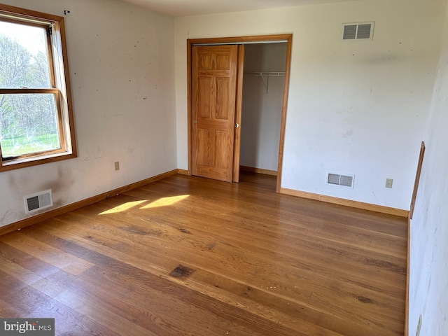 unfurnished bedroom featuring wood finished floors, baseboards, and a closet