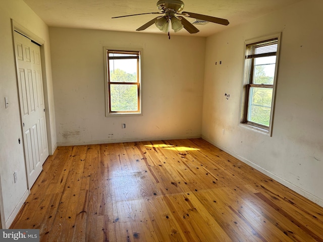 unfurnished bedroom featuring multiple windows, light wood-type flooring, and baseboards
