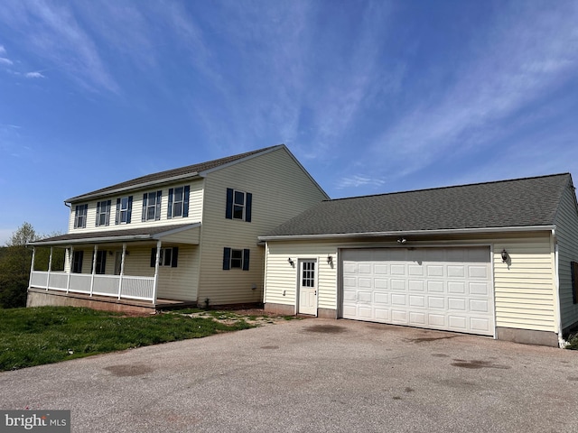 view of front of home with asphalt driveway, a garage, and a porch