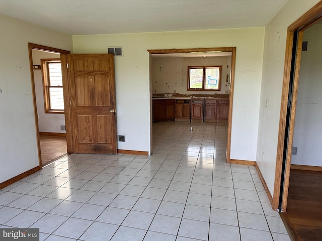 empty room with baseboards and light tile patterned floors