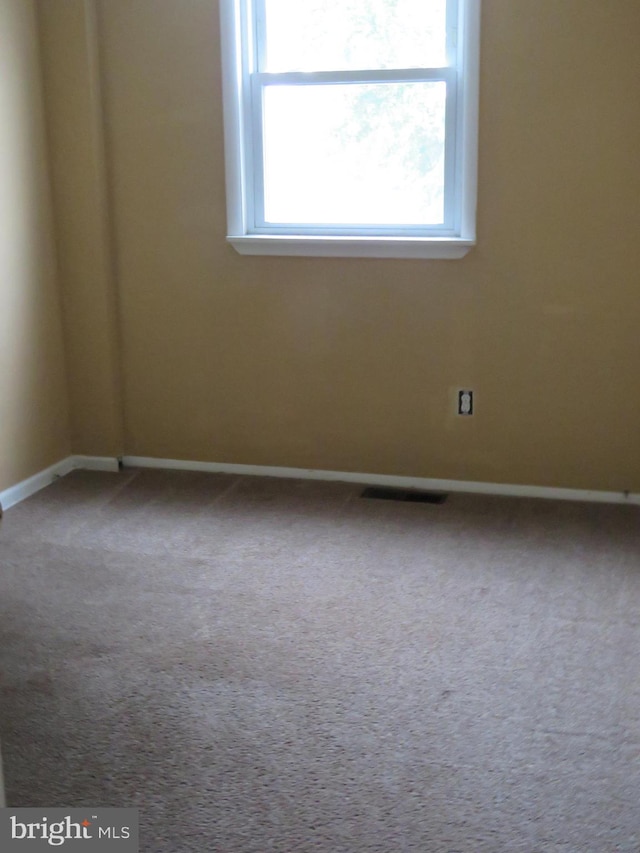 carpeted spare room featuring baseboards