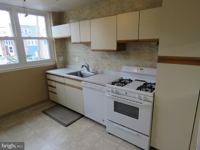 kitchen with white appliances, a sink, light countertops, tasteful backsplash, and decorative light fixtures