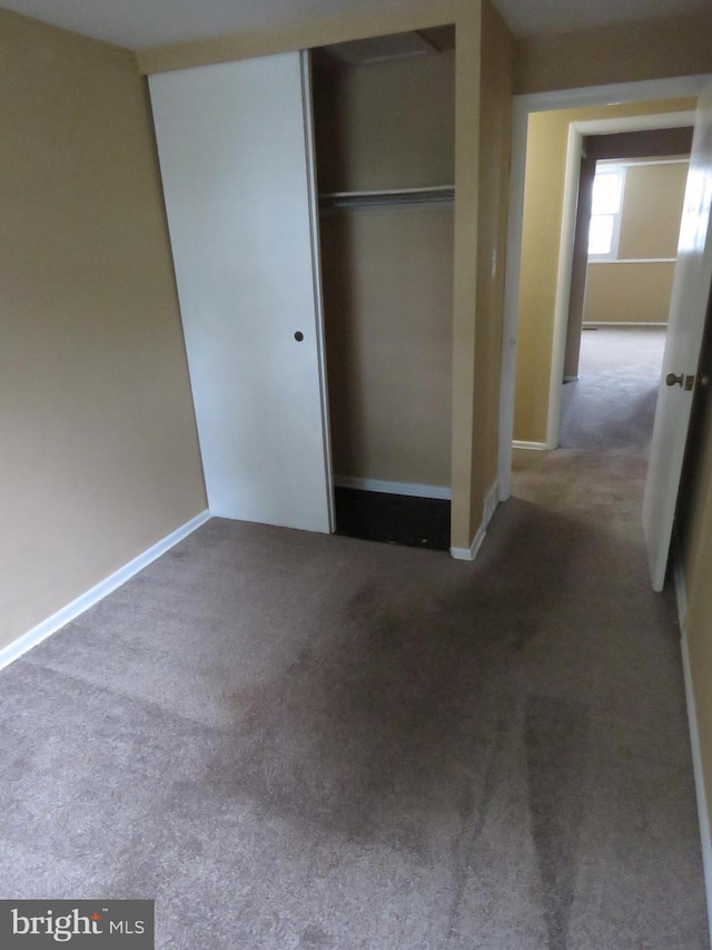 unfurnished bedroom with a closet, carpet, and baseboards
