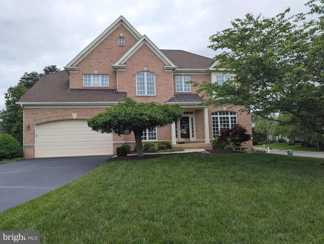 traditional home with brick siding, asphalt driveway, and a front lawn
