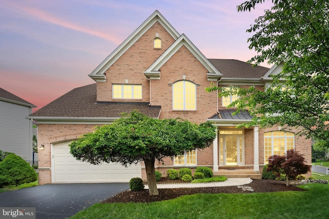 traditional-style home featuring brick siding, driveway, a shingled roof, and a front lawn