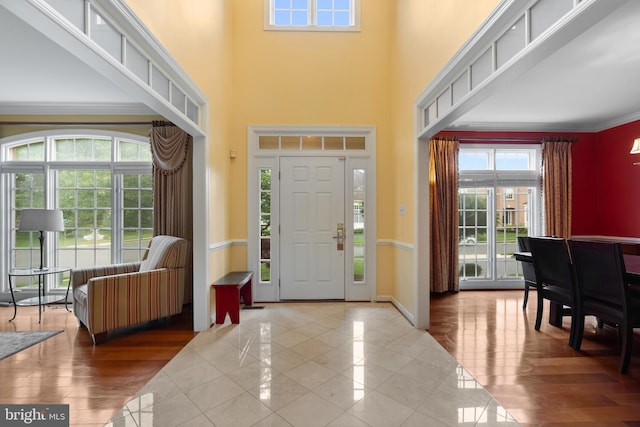 foyer entrance featuring a high ceiling, ornamental molding, baseboards, and tile patterned floors