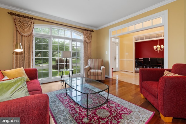 living area with crown molding, wood finished floors, a chandelier, and baseboards