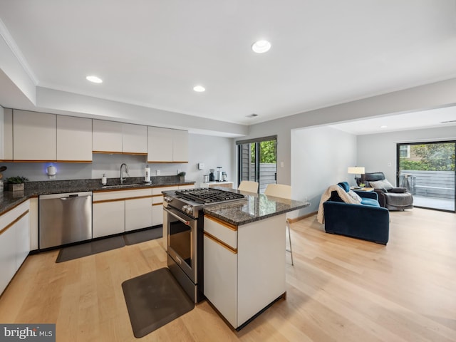 11041 Solaridge Dr, Reston, VA 20191 - kitchen featuring appliances with stainless steel finishes, a sink, light wood-style flooring, a breakfast bar area, and dark stone countertops