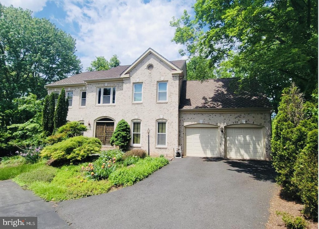 view of front of property featuring asphalt driveway, a garage, and brick siding
