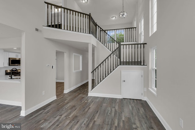 66 Cypress Pl, Newtown, PA 18940 - unfurnished living room with a towering ceiling, stairs, wood finished floors, baseboards, and a chandelier