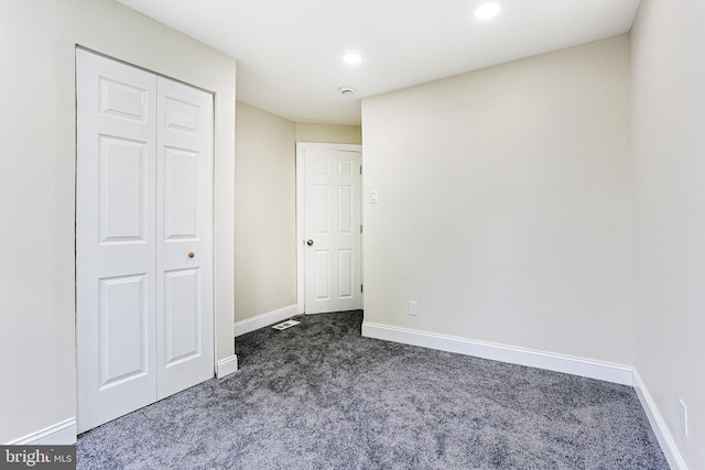 unfurnished bedroom featuring dark carpet, baseboards, recessed lighting, and a closet