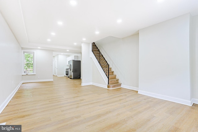 unfurnished living room with light wood-style floors, stairway, baseboards, and recessed lighting