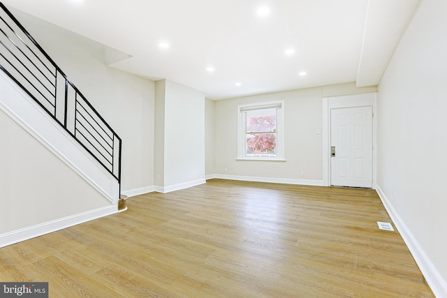 unfurnished living room with stairs, light wood-style flooring, baseboards, and recessed lighting