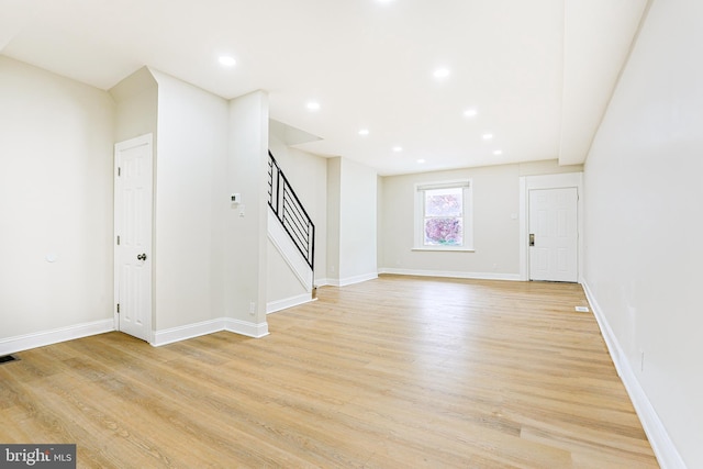 unfurnished living room featuring stairway, light wood finished floors, baseboards, and recessed lighting