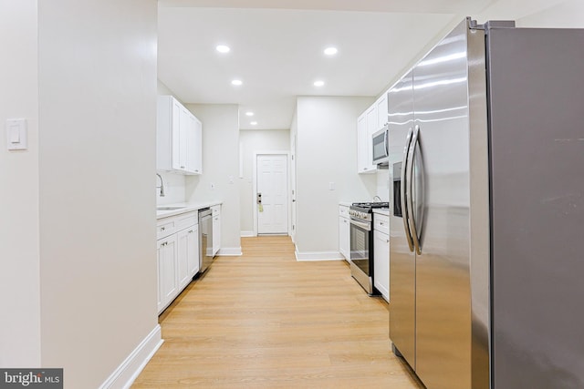 kitchen featuring appliances with stainless steel finishes, light wood-type flooring, white cabinetry, recessed lighting, and baseboards