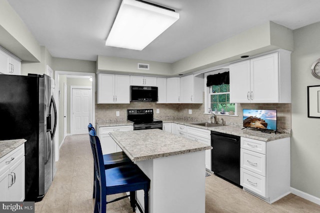 kitchen featuring black appliances, a sink, white cabinets, and a kitchen breakfast bar