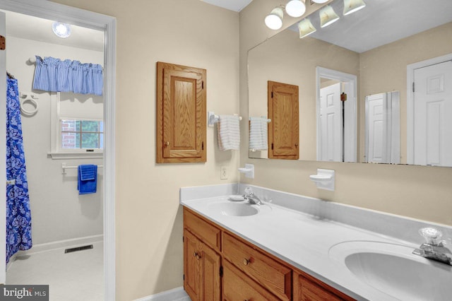 bathroom with double vanity and baseboards