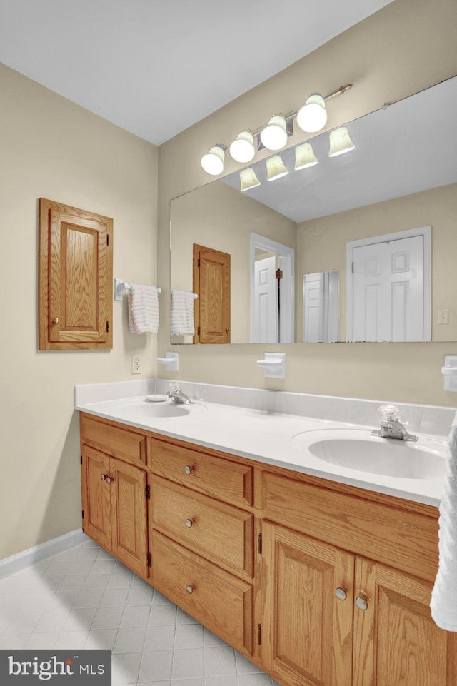 full bathroom with double vanity, tile patterned flooring, and baseboards