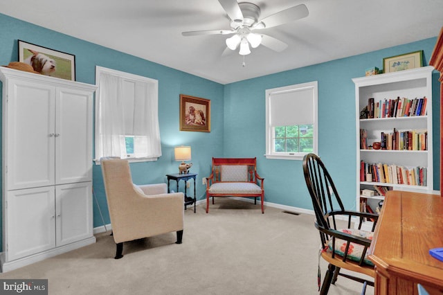 office space with light colored carpet, a ceiling fan, and baseboards