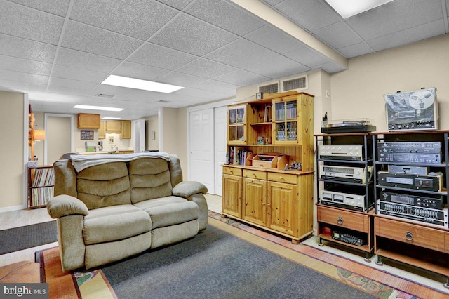 living area with a paneled ceiling and light colored carpet