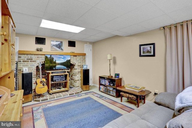 living room featuring a paneled ceiling and a brick fireplace