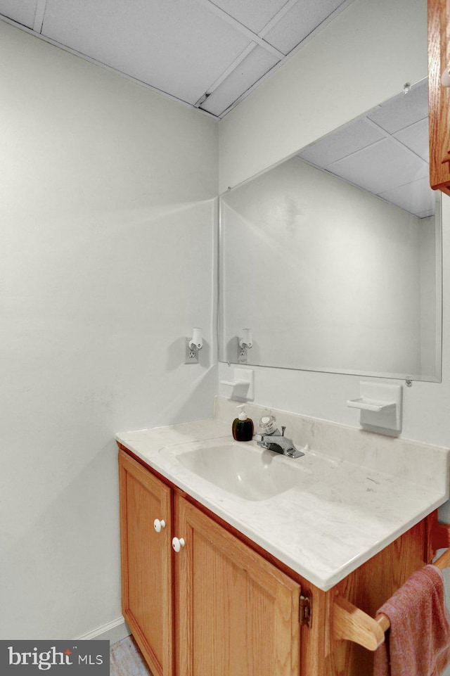 bathroom with vanity, a paneled ceiling, and baseboards