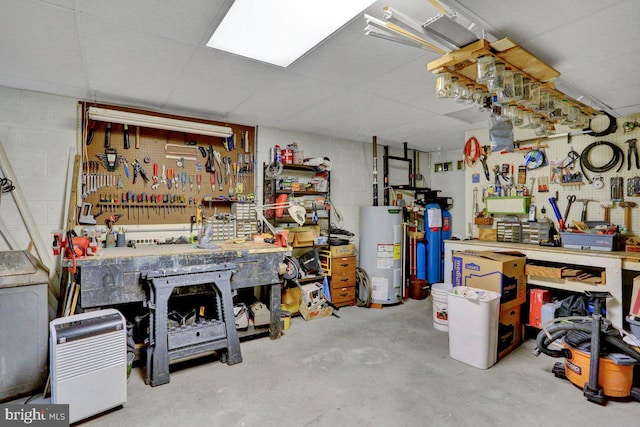 basement with a workshop area, water heater, and concrete block wall