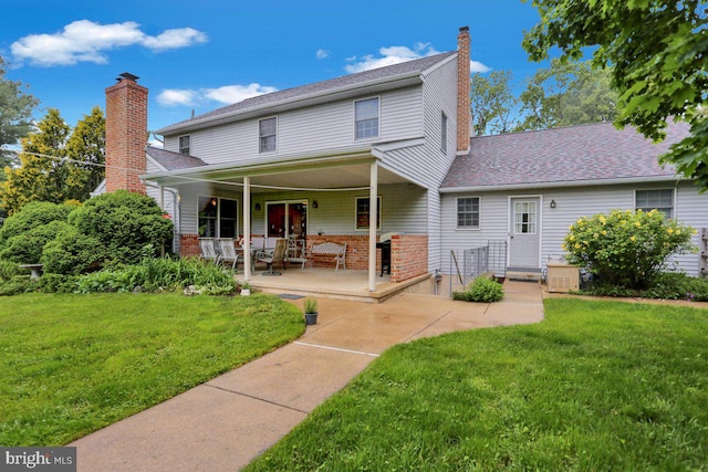 back of property featuring a yard, a chimney, a porch, and brick siding