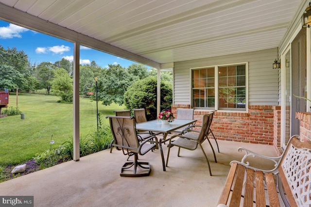 view of patio / terrace featuring outdoor dining area and view of wooded area