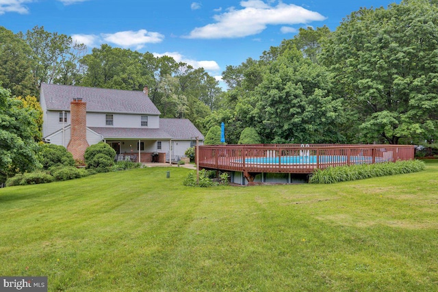 view of grassy yard with an outdoor pool and view of scattered trees