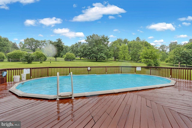 view of swimming pool with a wooden deck and view of scattered trees