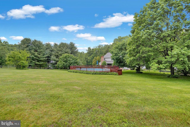 view of yard with a pool and a view of trees